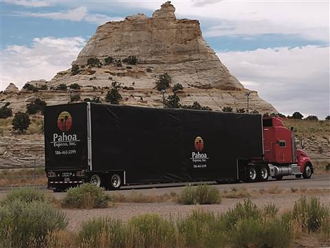 Pahoa black trailer semi truck in front of a mountain